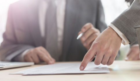 Hand of business woman pointing at document to senior businessman in office