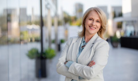 Smiling business woman with hands crossed outside corporate office